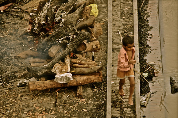Boy Running next to Ganges and Dead Body