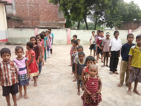 Children lining up in the yard, which is too hot in summer and too wet at monsoon.